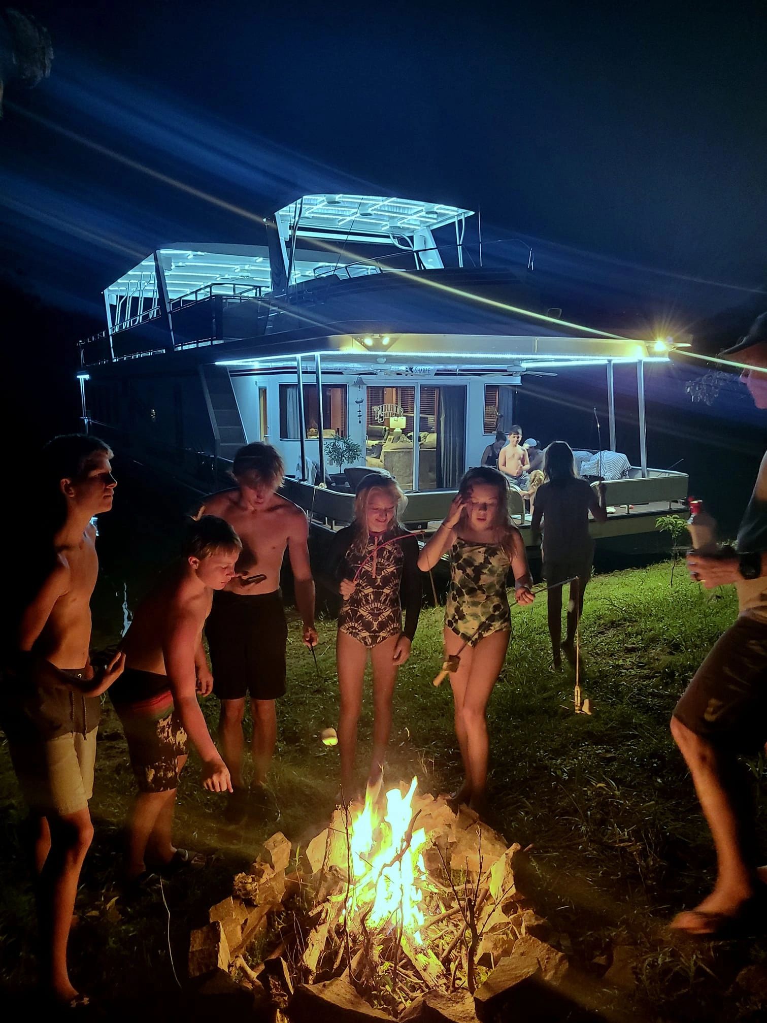 Nighttime gathering beside the illuminated houseboat
