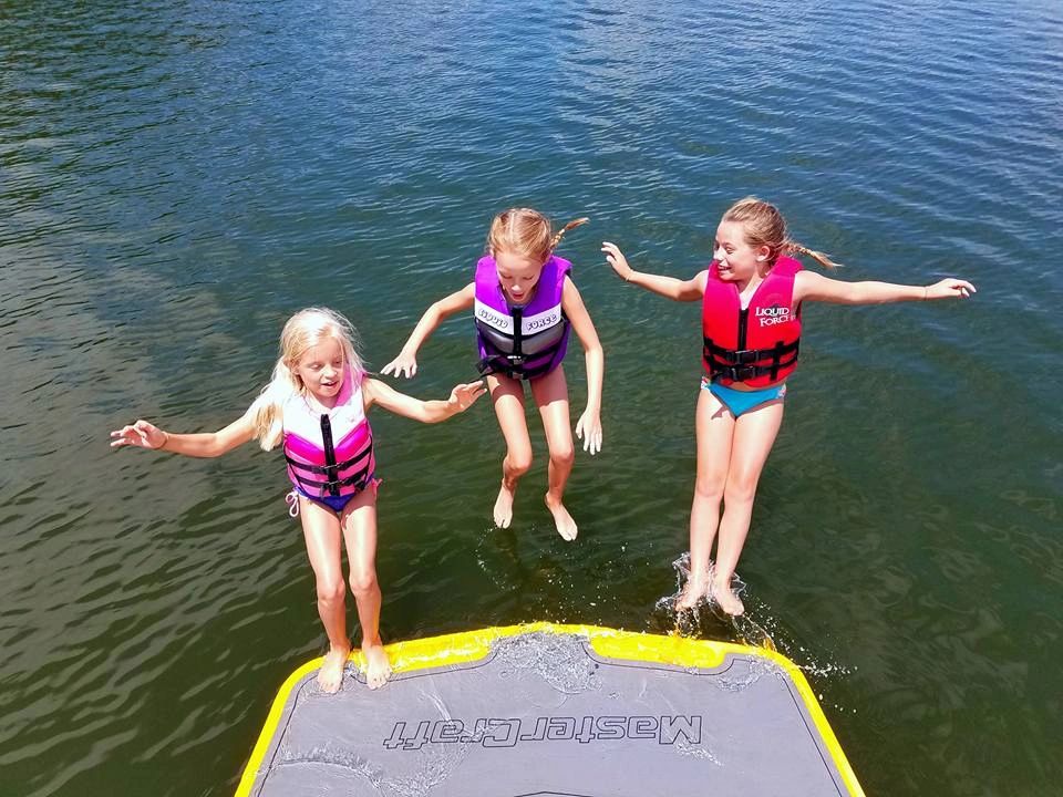 Children jumping from a lake water trampoline